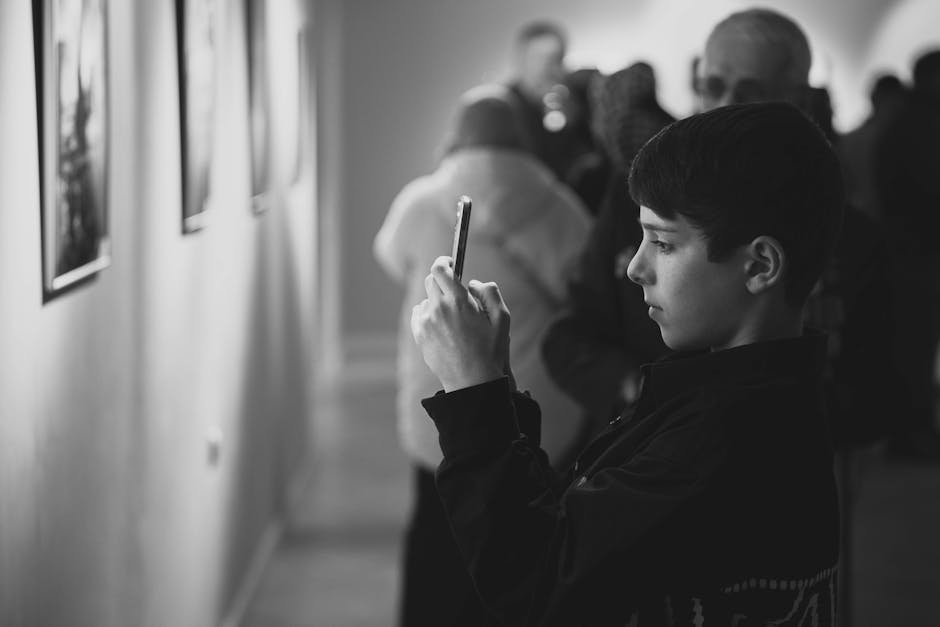 A teenager captures photos at a gallery exhibition using a smartphone.