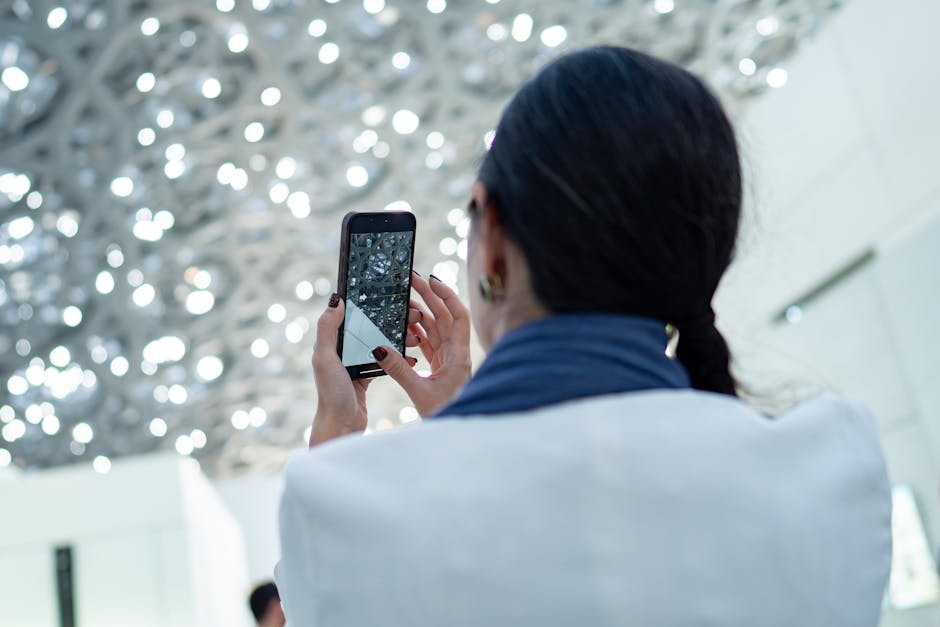 Woman photographing intricate ceiling design indoors using a smartphone.
