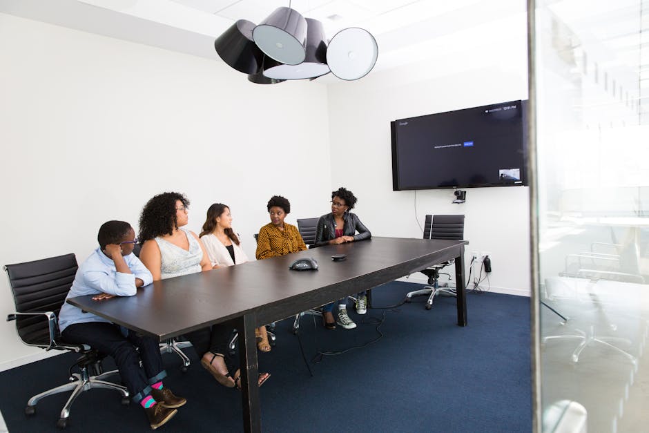 Group of diverse professionals engaged in a meeting in a modern office setting with technology integration.