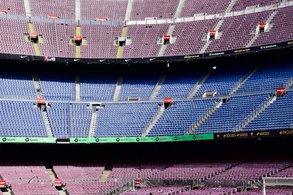 Wide-angle view of the empty stands at Camp Nou Stadium in Barcelona displaying vibrant seat colors.