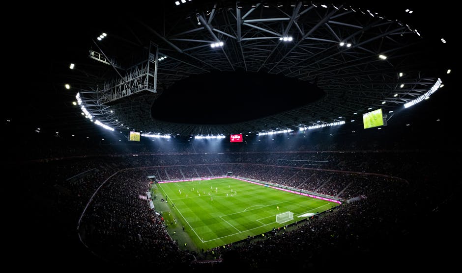 Aerial view of a night football match in Budapest. Illuminated stadium full of fans adds dramatic atmosphere.
